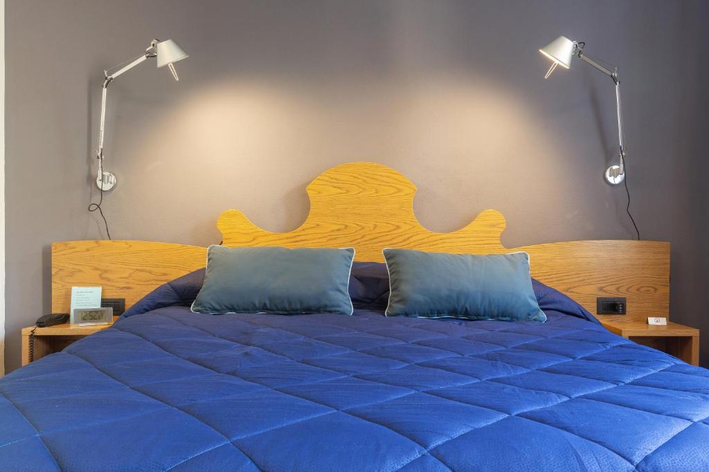 Malagigi Guest House في فيرّارا: غرفة نوم بسرير ازرق مع وسادتين ازرق