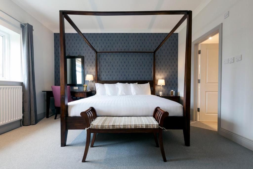 Asperion Hillside Hotel في غيلدفورد: غرفة نوم بها سرير مظلة مع مقعد وكرسي