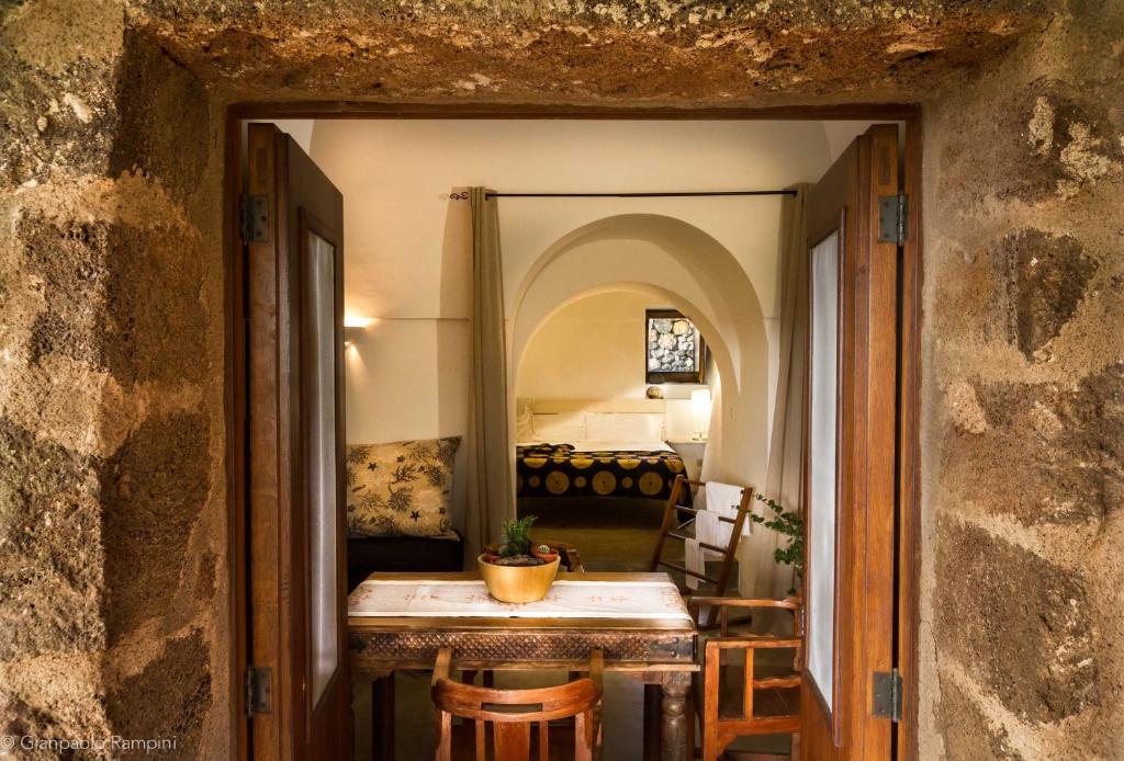 een hal met een tafel en een kamer met een bed bij 2 Gatti - Sogno in Pantelleria