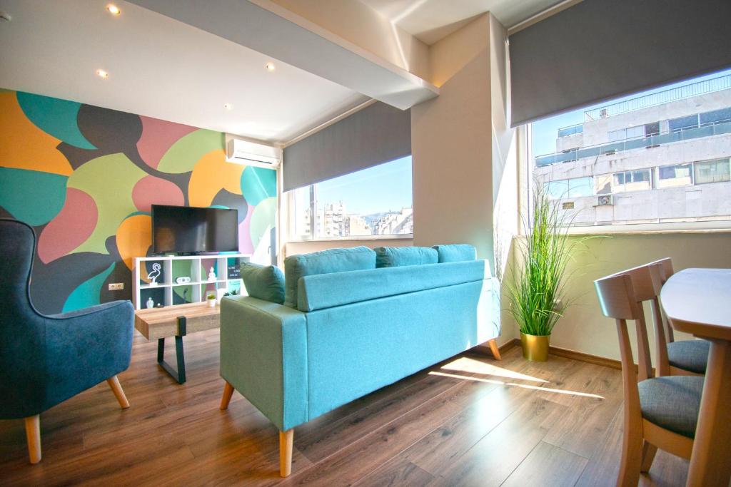 een woonkamer met een blauwe bank en een tafel bij Abstract Flat With Urban View in Athene