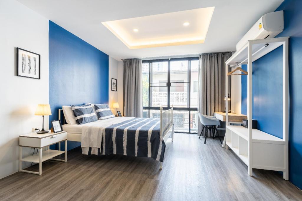 a bedroom with blue walls and a bed and a desk at Cozy Studio 1 in Sathorn, BTS Saint Louis in Bangkok