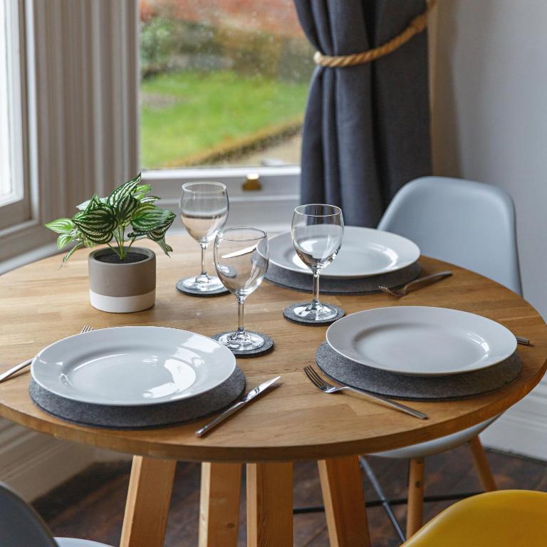 a wooden table with plates and wine glasses on it at The Sands Sheringham in Sheringham