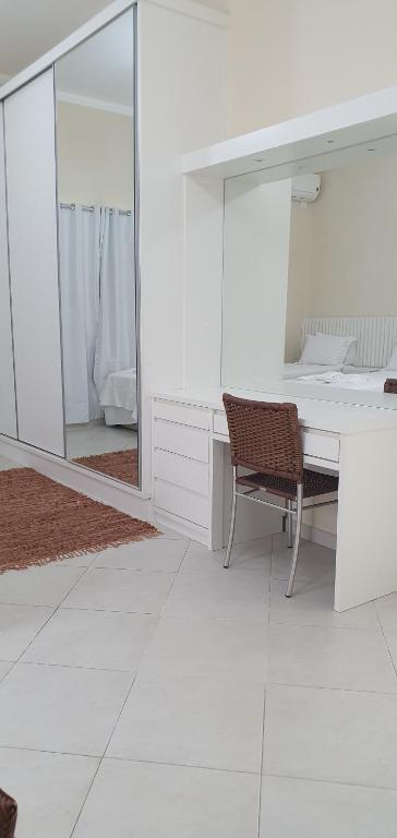 Habitación blanca con escritorio y espejo. en Cananeia Residencial, en Cananéia