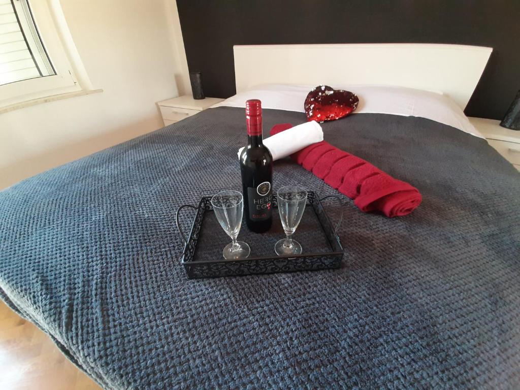een dienblad met een fles wijn en glazen op een bed bij FAMILY TIME in Split