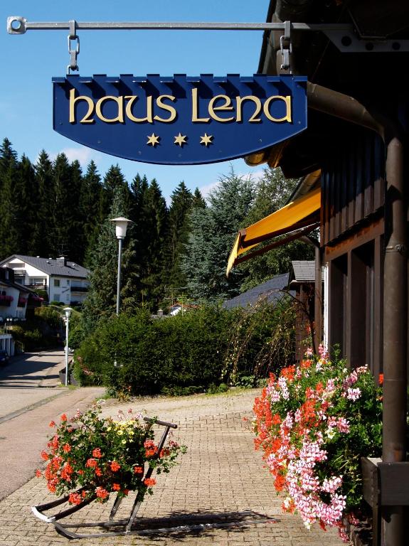 a sign on a building with flowers on a sidewalk at Landhaus Lena in Schönwald