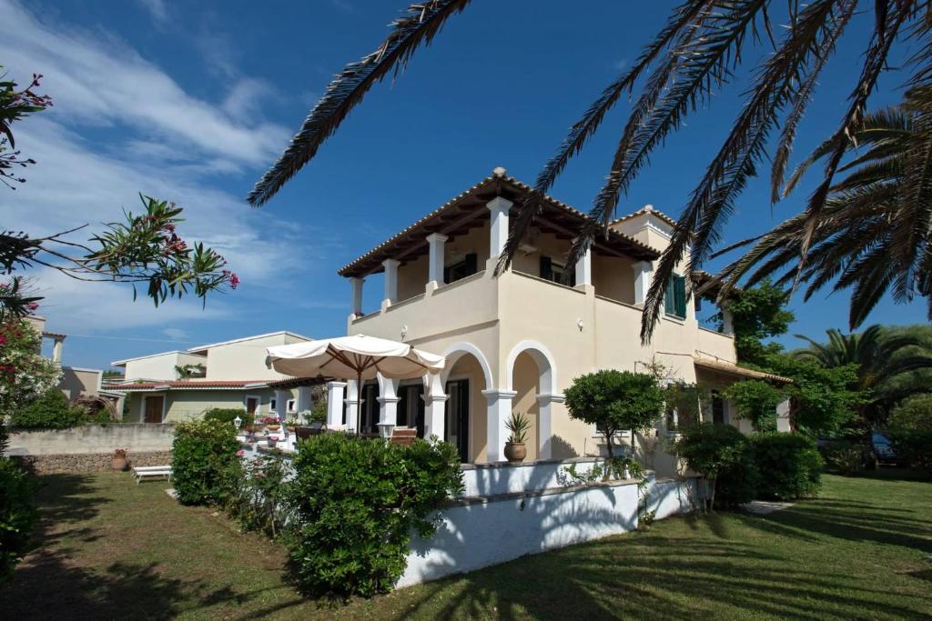 een wit huis met een palmboom bij Villa Diana in Acharavi