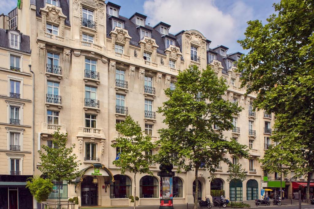 パリにあるHoliday Inn Paris - Gare de Lyon Bastille, an IHG Hotelの木々が目の前に広がる日焼けの建物