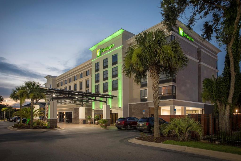 ein Hotel mit Autos auf einem Parkplatz in der Unterkunft Holiday Inn Pensacola - University Area, an IHG Hotel in Pensacola
