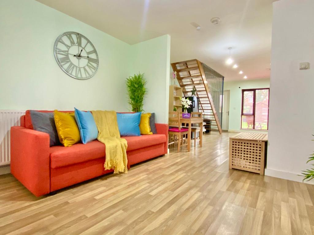 a living room with a red couch and a clock at Spacious 5 bed townhouse Manchester, Salford Qauys - Two Bedroom with Parking in Manchester