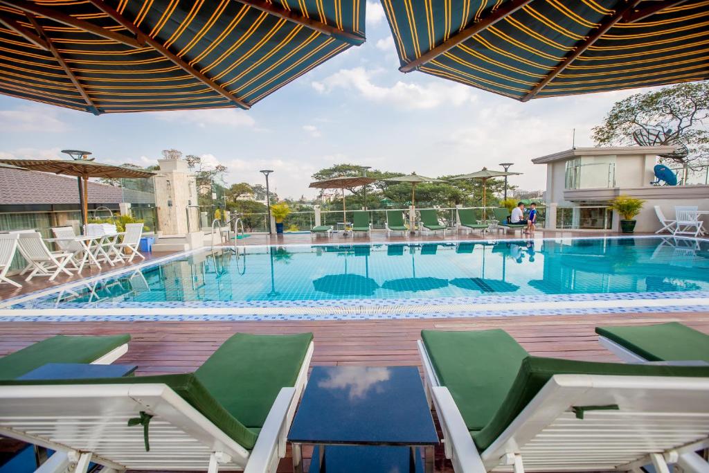 einen großen Pool mit Stühlen und Tischen in der Unterkunft Prestige Residences at Golden Valley by Grand United Hospitality in Yangon