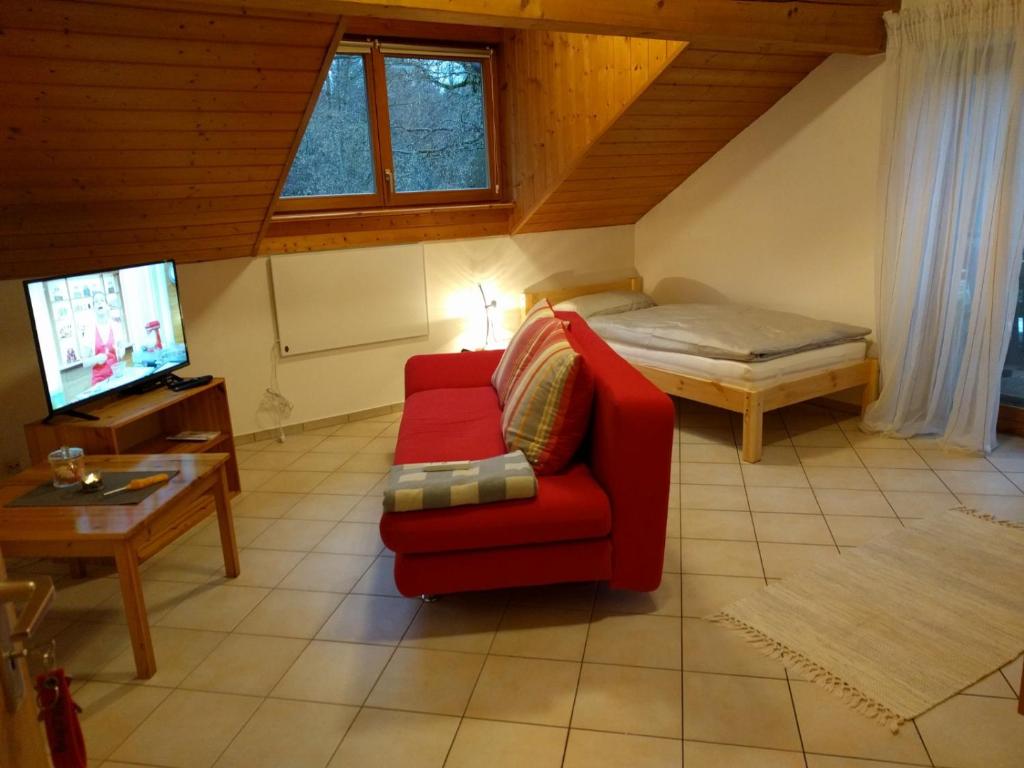 a living room with a red chair and a bed at Komfortabel wohnen am Waldrand von Pitzling in Landsberg am Lech