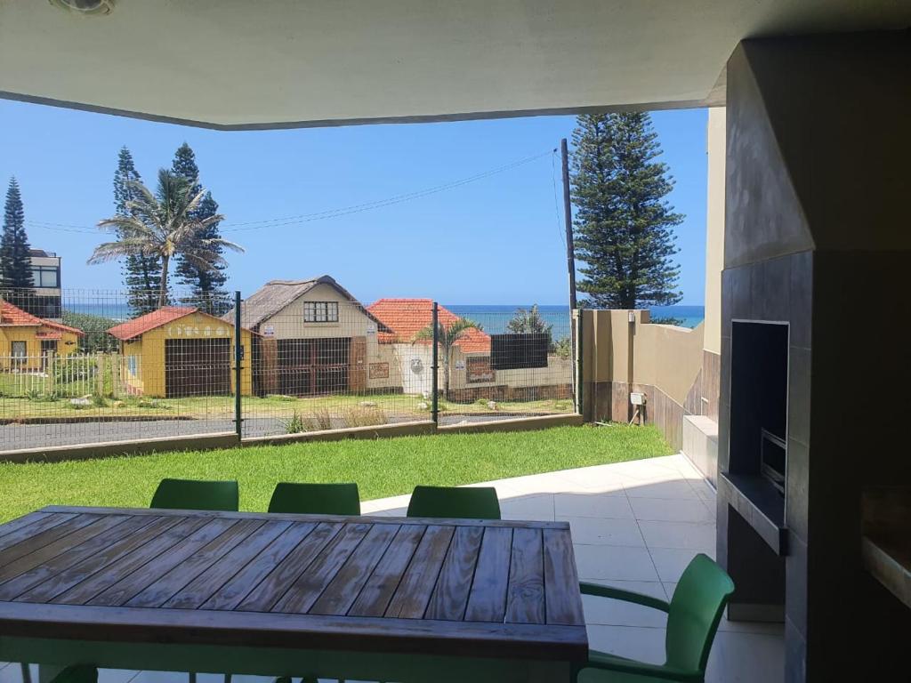 - une table à manger avec des chaises et une vue sur la cour dans l'établissement Saints View Resort Unit 1, à Uvongo Beach