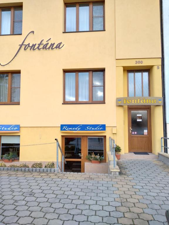 un edificio amarillo con un cartel. en Pension Fontana, en Poděbrady