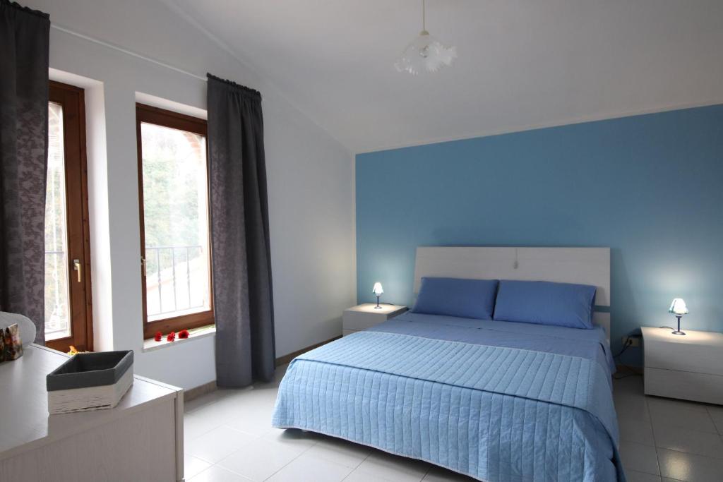 een blauwe slaapkamer met een bed en 2 ramen bij Casa Vacanze Al Borgo in Caprino Veronese