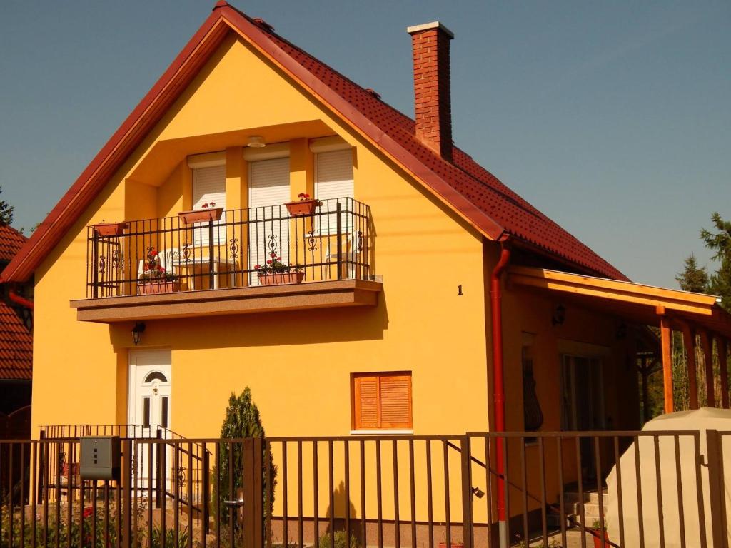 una casa gialla con balcone e recinzione di Bükki Vendégház a Balatonmáriafürdő