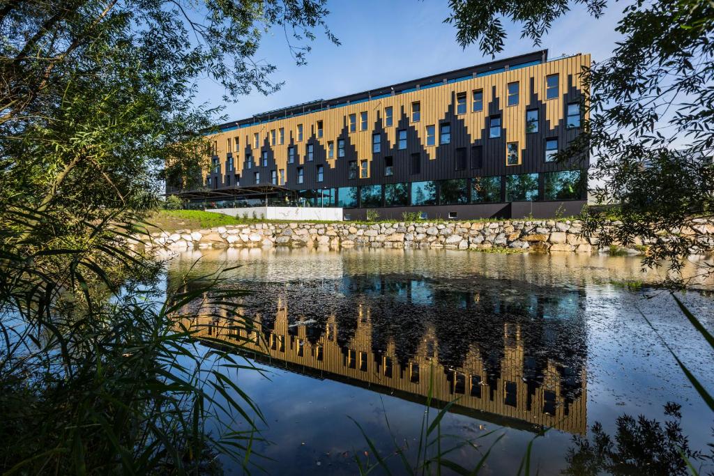 un edificio con un reflejo en un cuerpo de agua en MY HOME MY HOTEL Rosenheim en Rosenheim