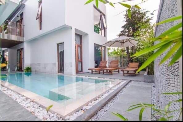 Casa con piscina con bancos y sombrilla en Green World Hoi An Villa en Hoi An