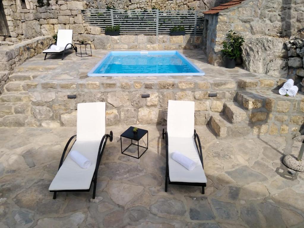een patio met 2 stoelen en een zwembad bij Holiday Home Brotnice in Cavtat