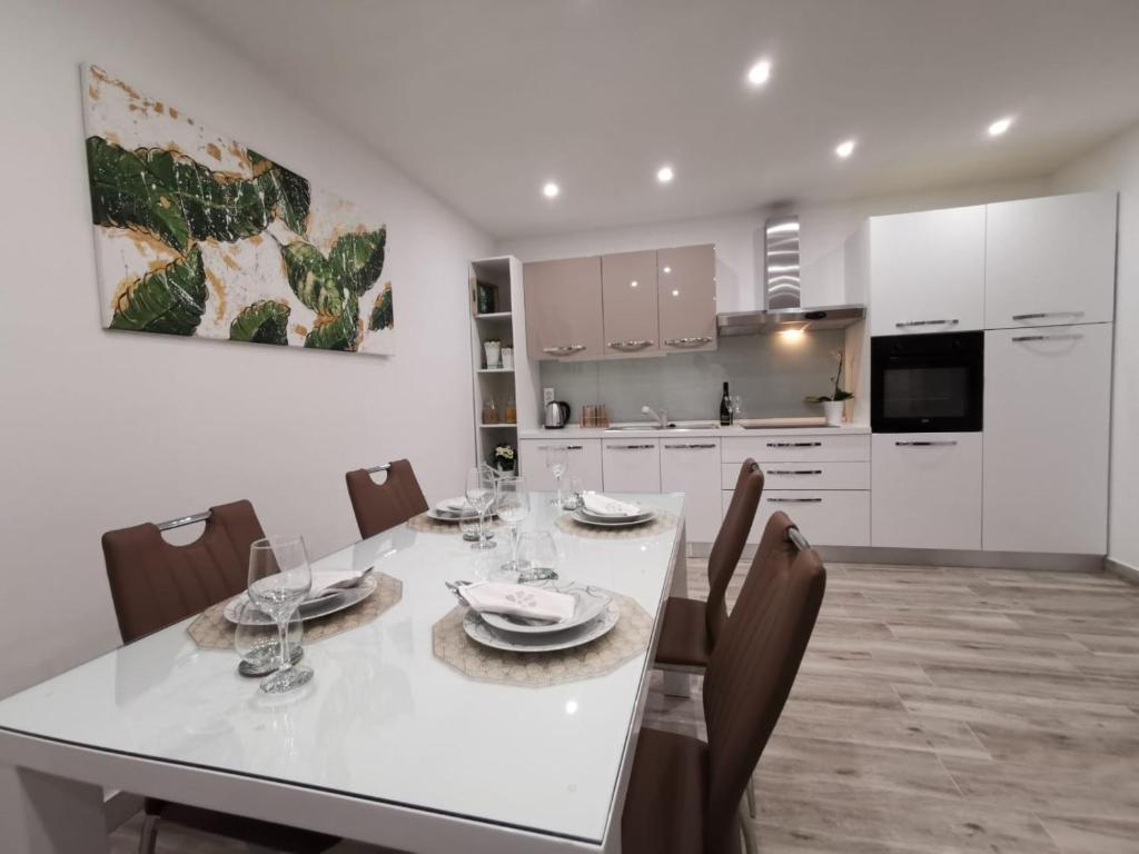 eine weiße Küche mit einem Esstisch und Stühlen in der Unterkunft Apartmani Pina 1 in Kaštela