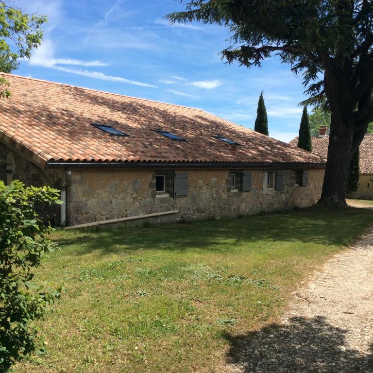 an old stone house with a tree in the yard at gites Les Lebes - Grange loft in Sempesserre