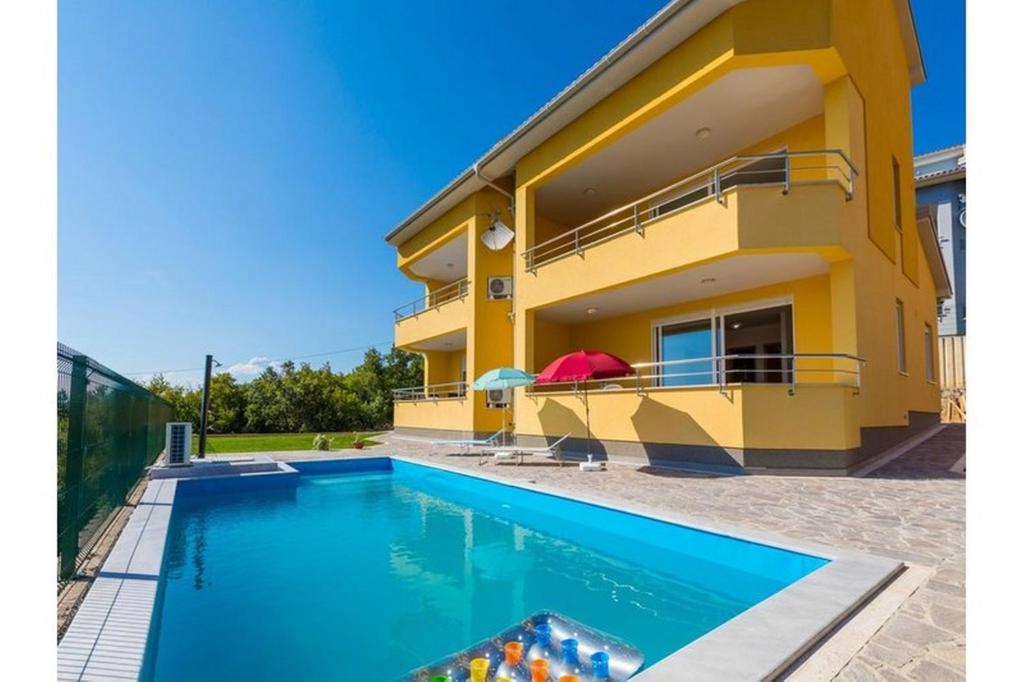 a yellow house with a swimming pool in front of it at Apartment Heaven Hill in Jadranovo