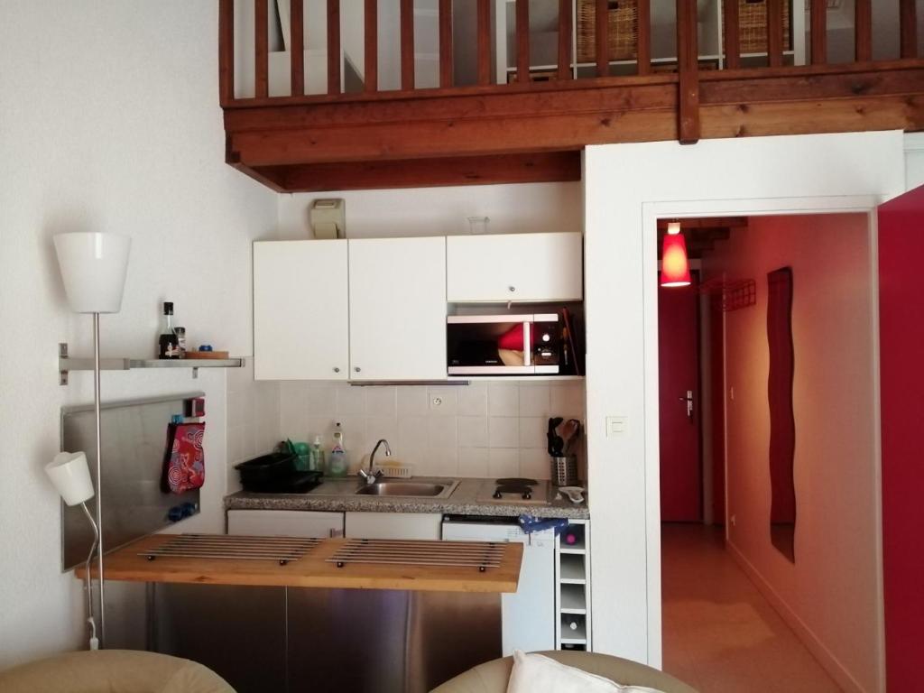 une petite cuisine avec un évier et un micro-ondes dans l'établissement Le Soleil et la Mer, à Pornichet