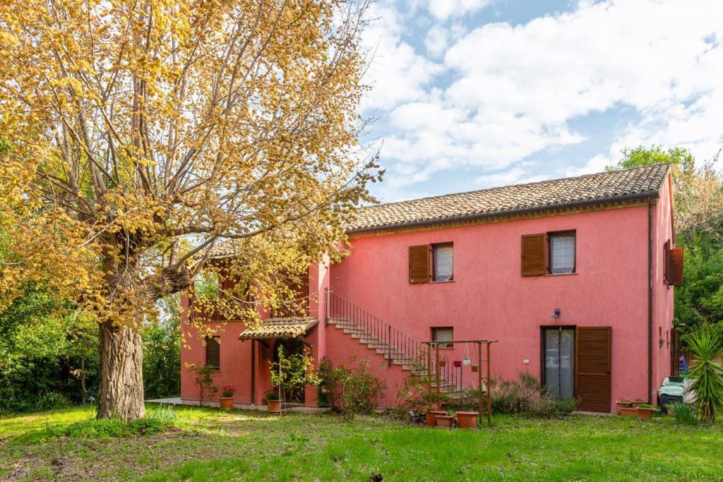 una casa roja con un árbol delante en Il Casale degli Allori a 20 minuti dalla Riviera del Conero, en Polverigi