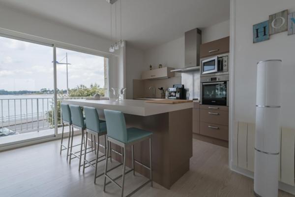 uma cozinha com um balcão e cadeiras e uma grande janela em Appartement vue mer em Bénodet