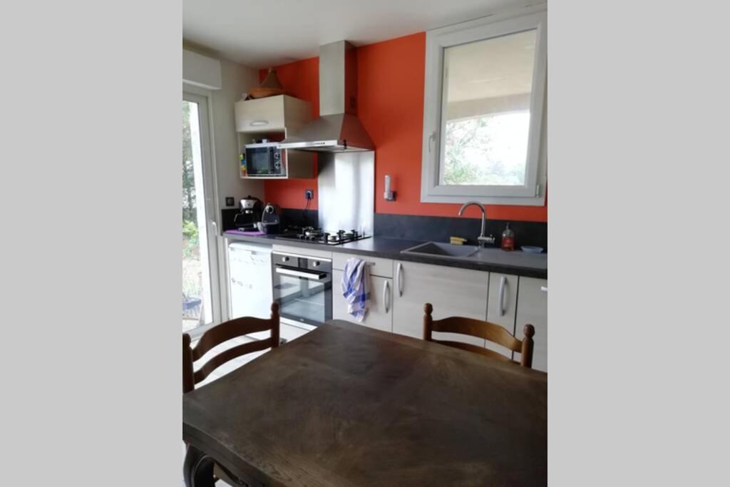 kuchnia z pomarańczowymi ścianami i drewnianym stołem w obiekcie Appartement 2 pièces sur jardin en Pic Saint-Loup w mieście Valflaunès