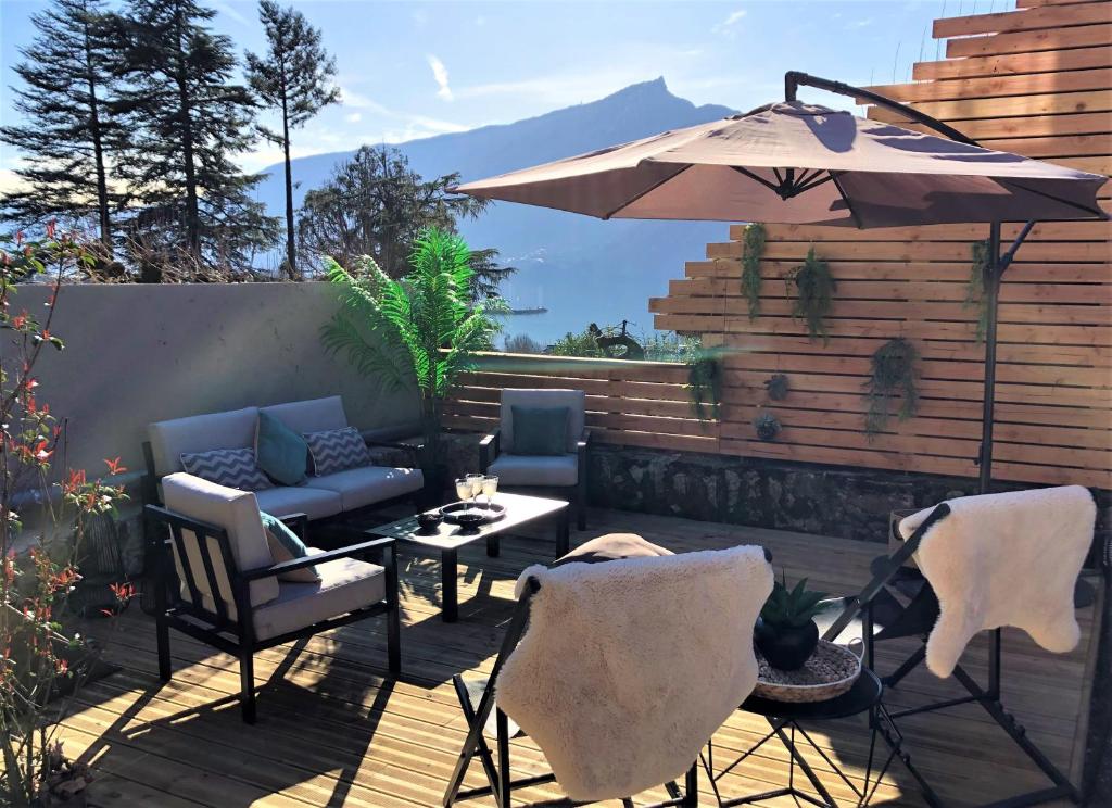 une terrasse avec une table, des chaises et un parasol dans l&#39;établissement Loft Christina moderne et confortable, vue lac, climatisation, parking, à Aix-les-Bains