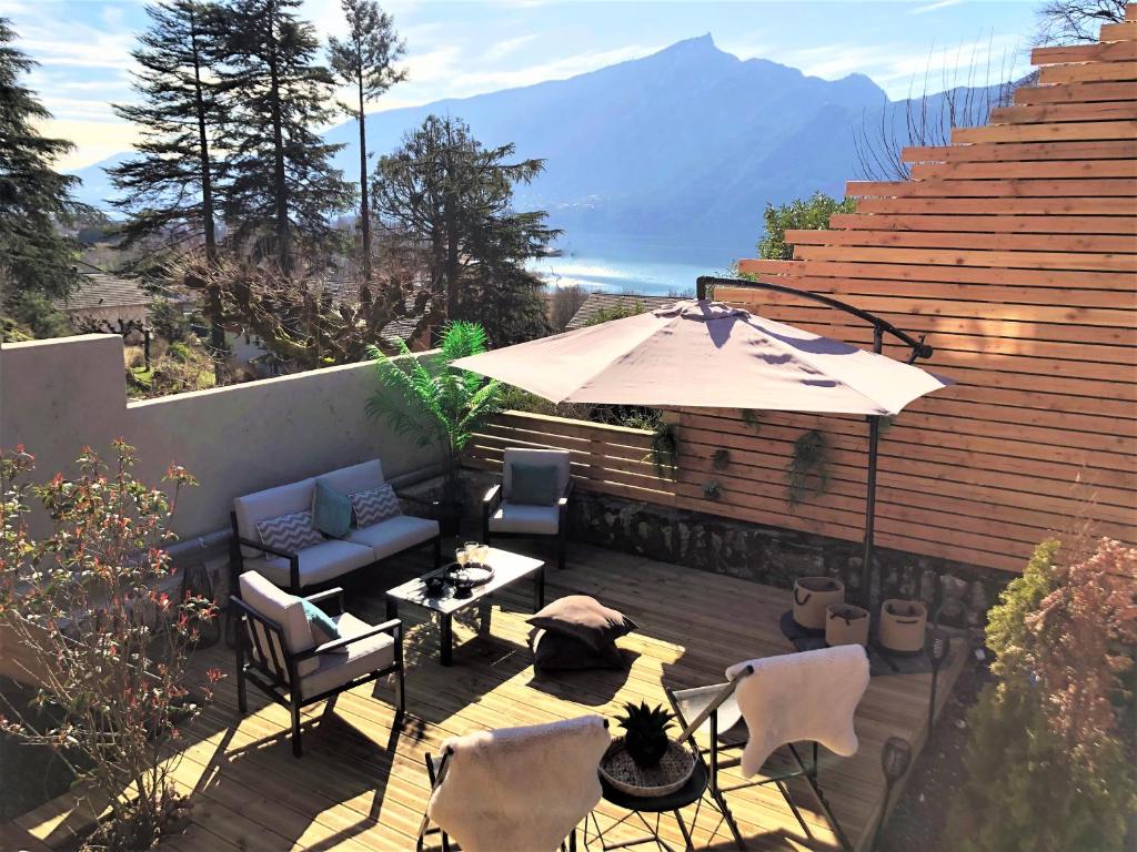 un patio con sombrilla, mesa y sillas en Loft Christina moderne et confortable, vue lac, climatisation, parking, en Aix-les-Bains