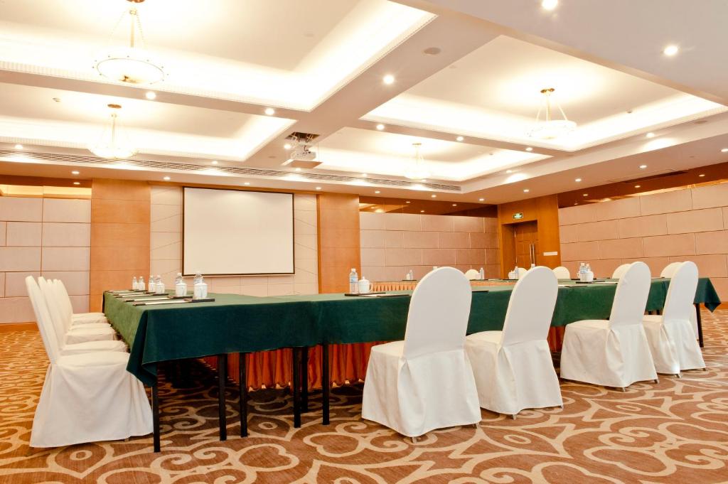 uma sala de conferências com uma mesa verde e cadeiras brancas em Holiday Inn Shanghai Pudong, an IHG Hotel em Xangai