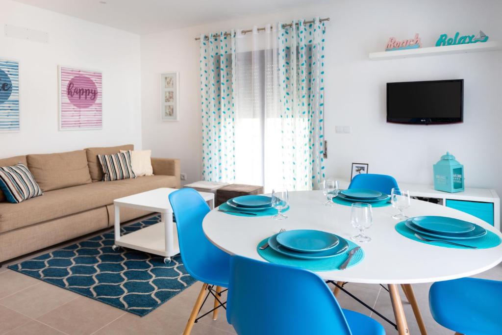 a living room with a white table and blue chairs at Keep Calm and Enjoy Nazaré in Nazaré