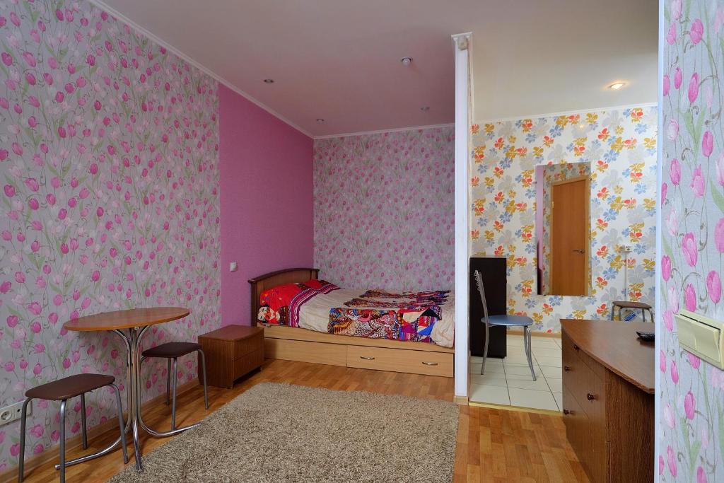 オムスクにあるOmskSutki Apartments on Tsyolkovskogo st.のベッドルーム1室(ベッド1台、テーブル、椅子付)