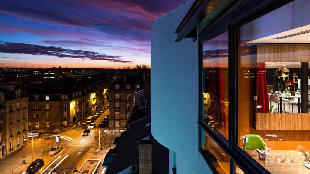 uma vista de uma janela de uma cidade ao anoitecer em Holiday Inn Reims Centre, an IHG Hotel em Reims