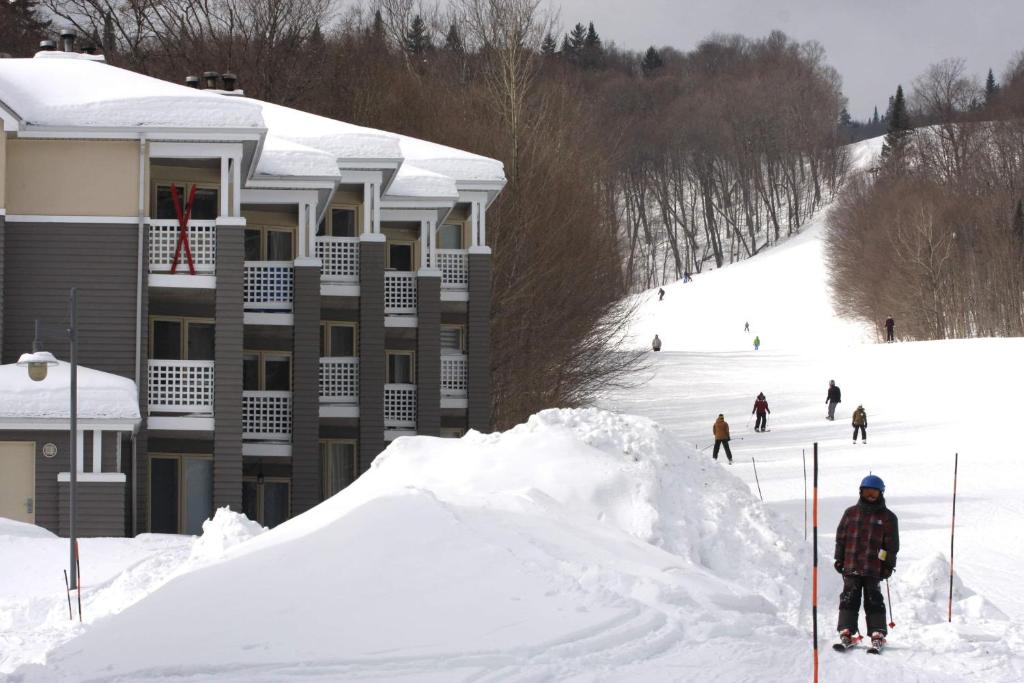 un grupo de personas esquiando por una pista cubierta de nieve en Ski-in, ski-out chaleureux studio loft au pied des pistes de ski en Stoneham