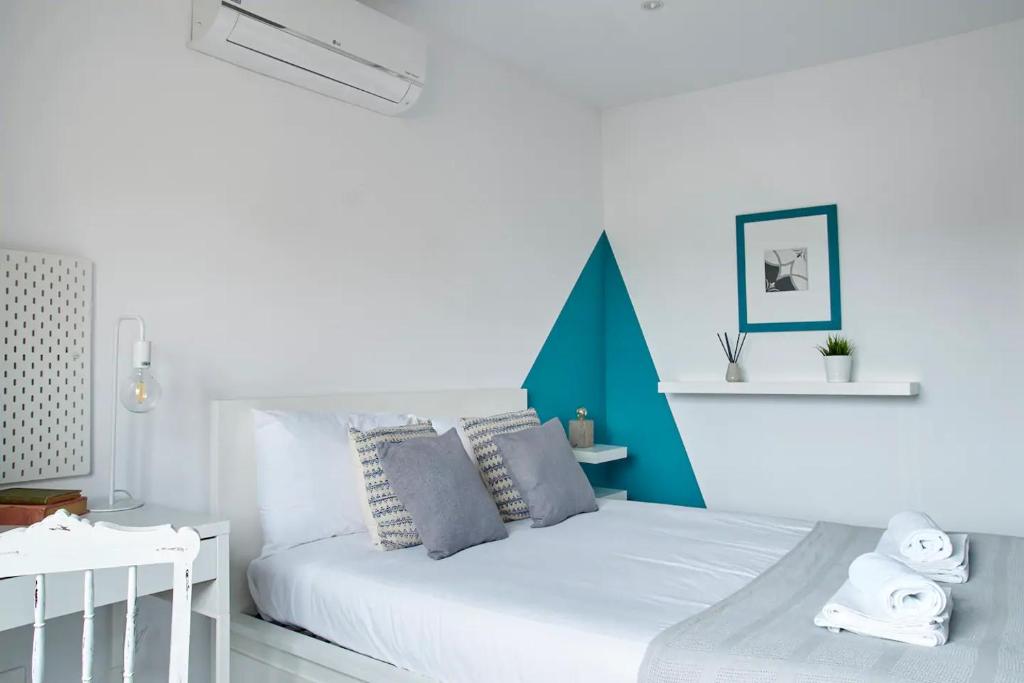 - une chambre avec un lit blanc et des murs bleus dans l'établissement Alegria 79 - Fabulous 3 Bedroom House, à Coimbra