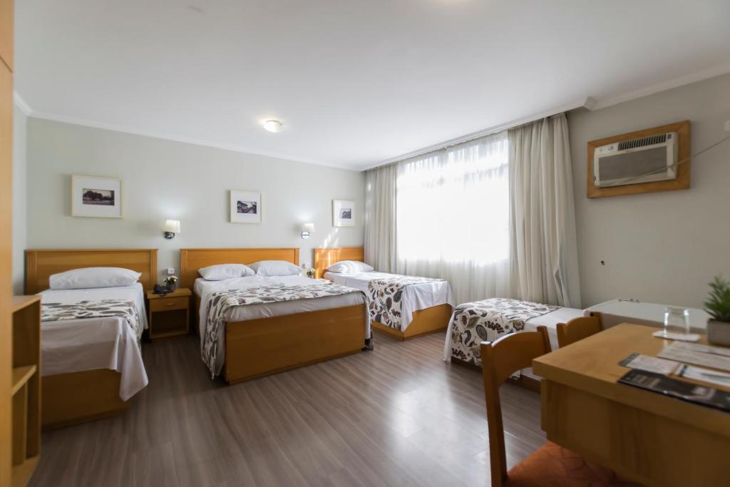 a hotel room with three beds and a table at Paulista Garden Hotel in Sao Paulo