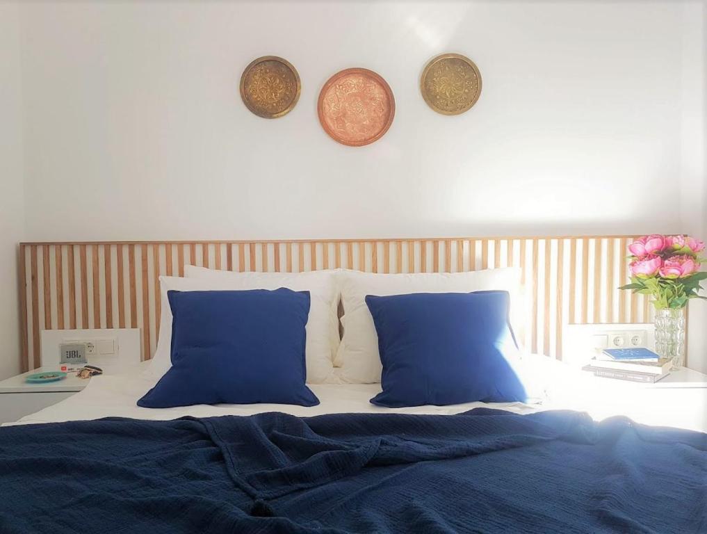 a bed with blue pillows and plates on the wall at Spitaki Apartments Potos in Potos