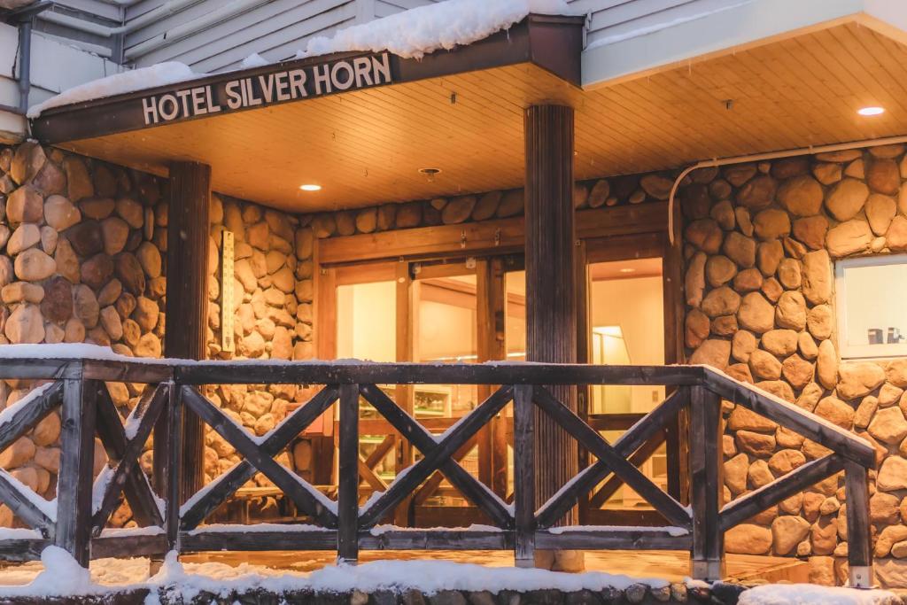 a hotel exterior with a wooden fence in front of a building at Silverhorn in Myoko