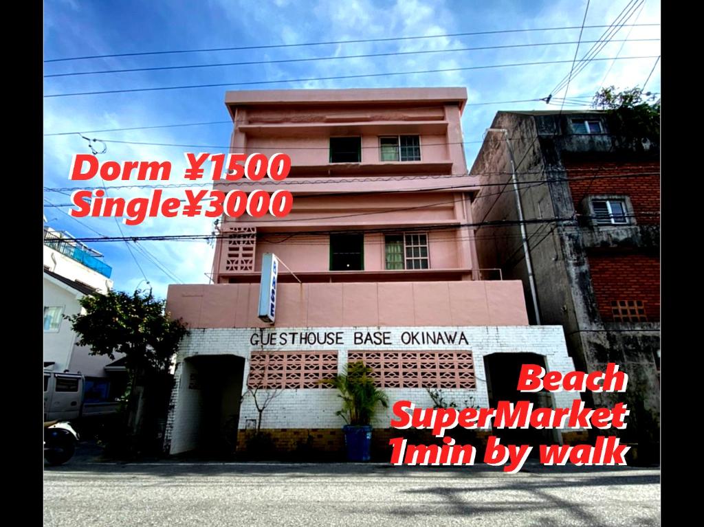 a pink building with a sign in front of it at Guesthouse Base Okinawa in Naha