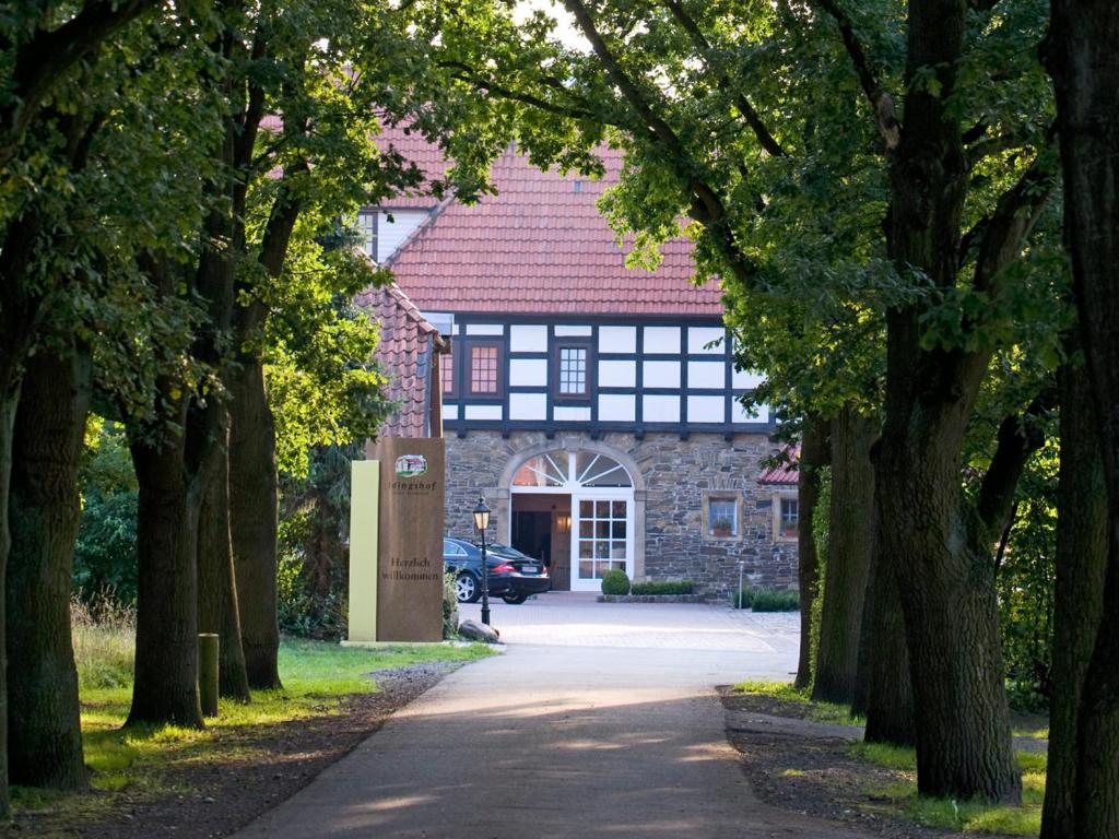 a stone house with a driveway leading to a building with trees at IDINGSHOF Hotel & Restaurant in Bramsche