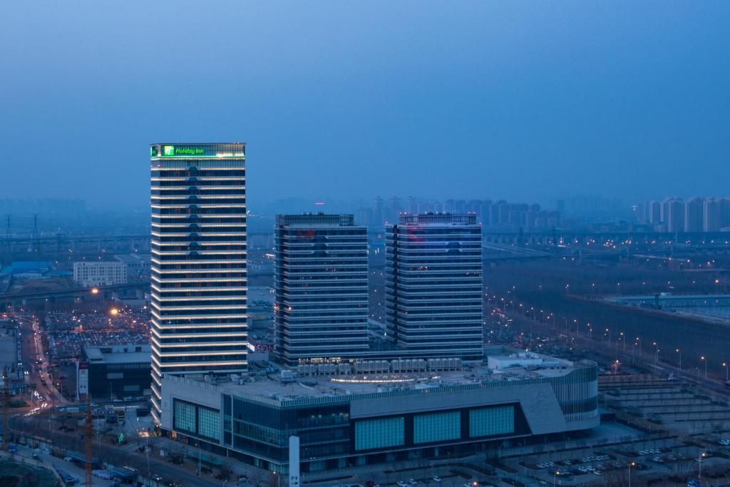 天津的住宿－天津中北假日酒店，一群高大的建筑在晚上在城市里
