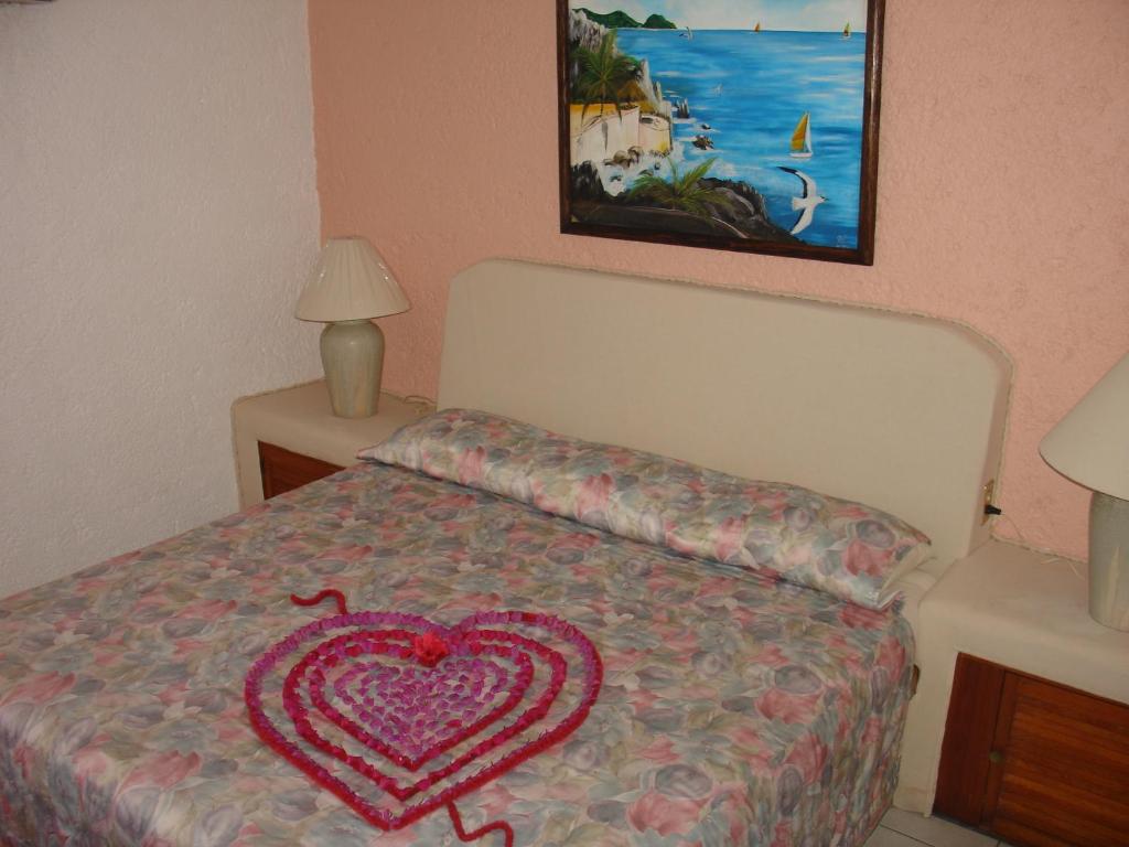 a bedroom with a bed with a heart pillow on it at Coral Ixtapa in Ixtapa