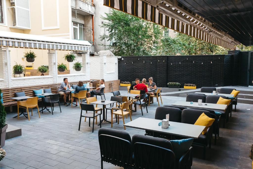 a patio with tables and chairs and people sitting at Discovery Hotel in Lviv