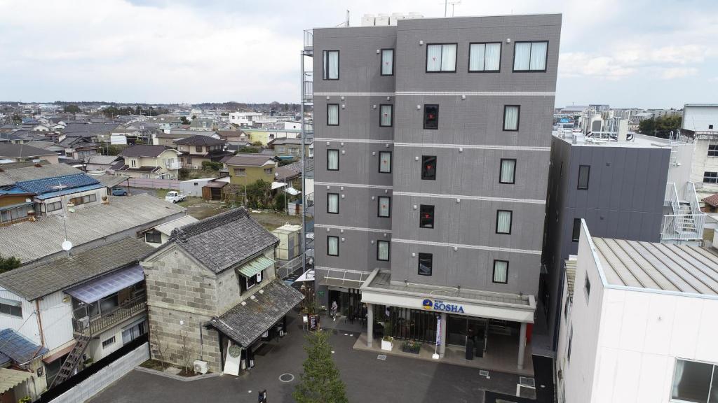 a tall gray building in a city with buildings at HOTEL SOSHA in Ishioka