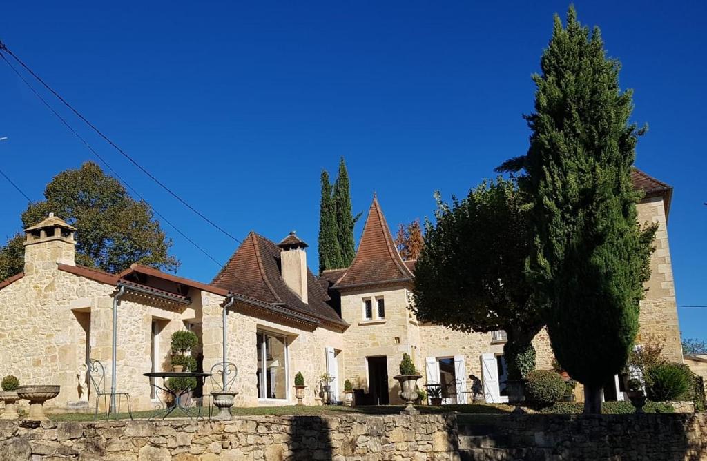 una grande casa in pietra con un albero di fronte di Au Clos de Mathilde a Sarlat-la-Canéda