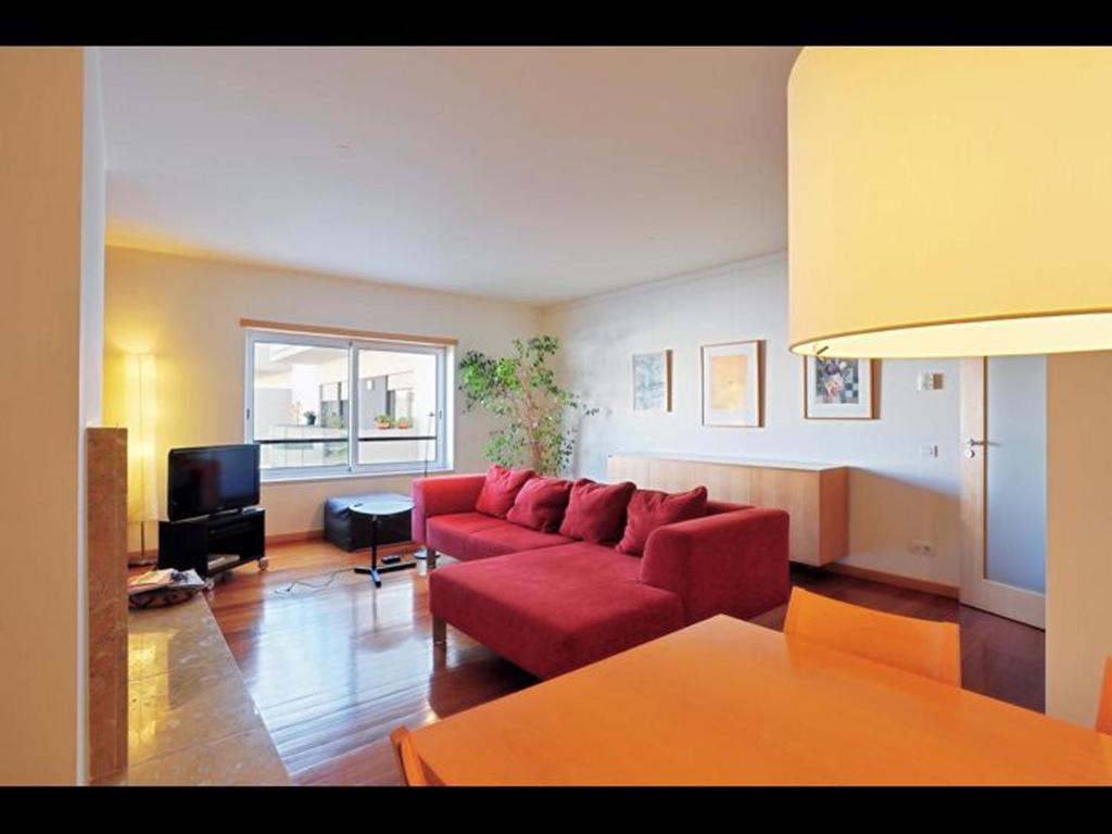salon z czerwoną kanapą i telewizorem w obiekcie Confortable & contemporary - Expo w Lizbonie