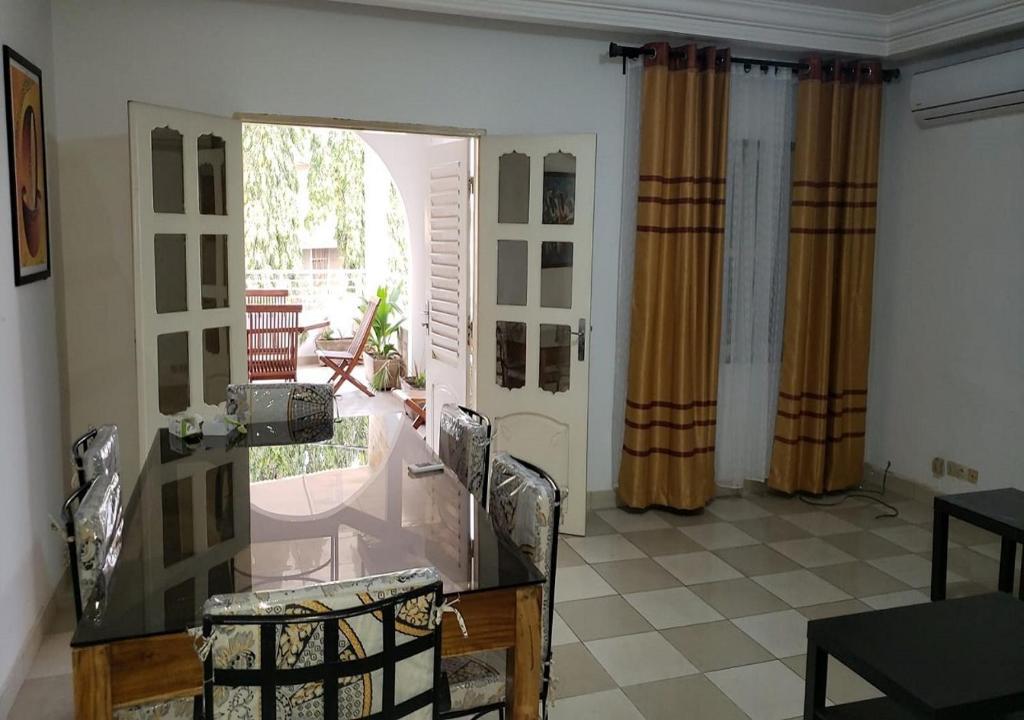 a living room with a glass table and chairs at iléos, appartement meublé 4 pièces - Salon, cuisine, 3 chambres Lomé Tokoin Hôpital Protestant in Lomé