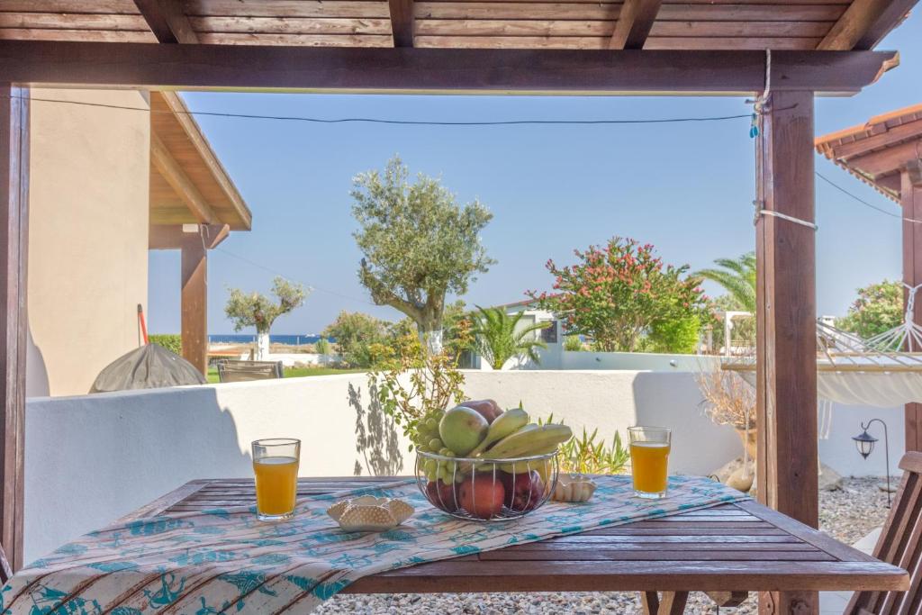 a table with a bowl of fruit and two glasses of orange juice at Renes Paradise Seahome - Afandou Beach, Rhodes in Rhodes Town